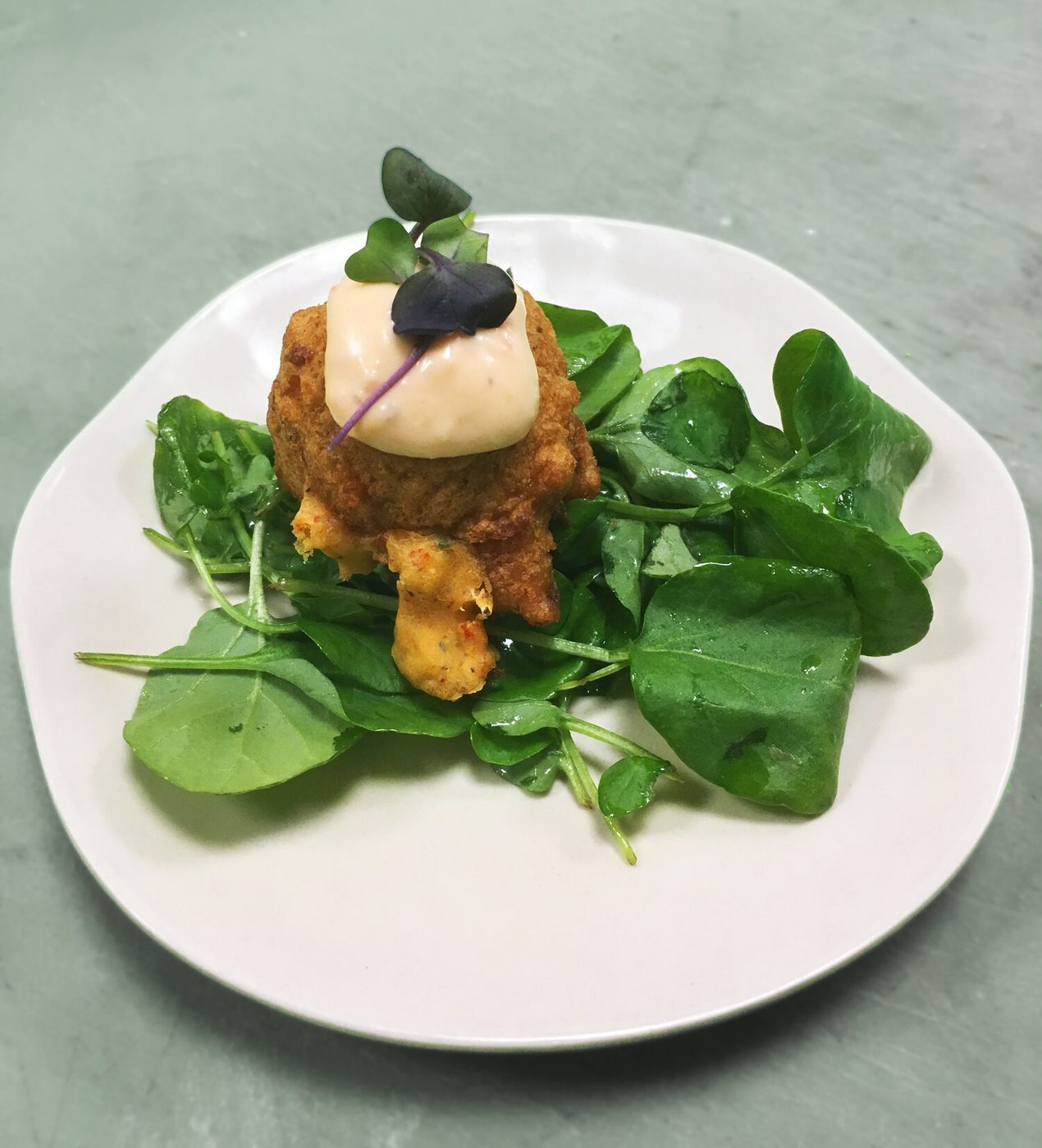 Crab cake with aioli and microgreens on watercress