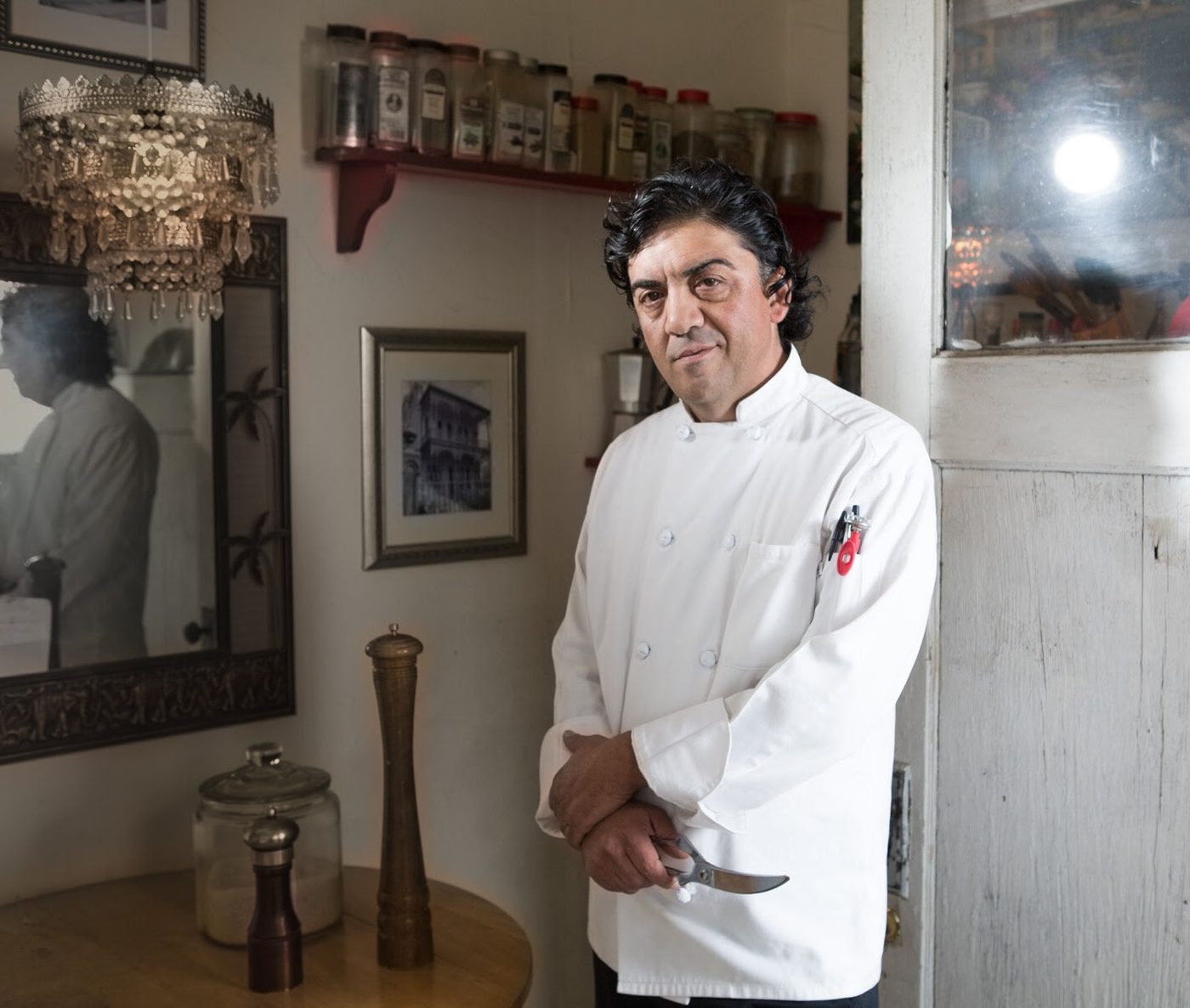 Izzy Abunimeh in chef’s whites, standing in a kitchen